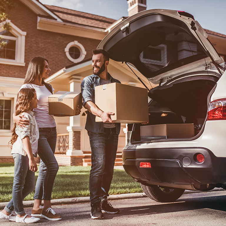 Family unpacking car in front of home